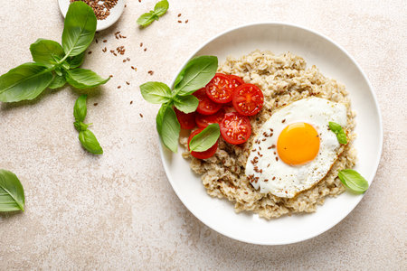 Oatmeal with fried sunny-side-up egg, tomatoes and basil, top viewの写真素材
