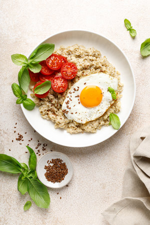 Oatmeal with fried sunny-side-up egg, tomatoes and basil, top viewの写真素材