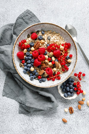 Muesli with organic berries and nuts. Oat muesli with raspberry, blueberry, red currant, almond, pecan, walnut, cashew, hazelnut and pumpkin seeds. Healthy food, top viewの写真素材