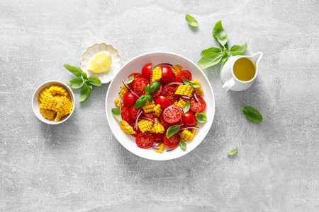 Tomato and corn salad with fresh basil, onion, dressed with olive oil. Mexican food, tomato corn salad Esquites, top viewの写真素材