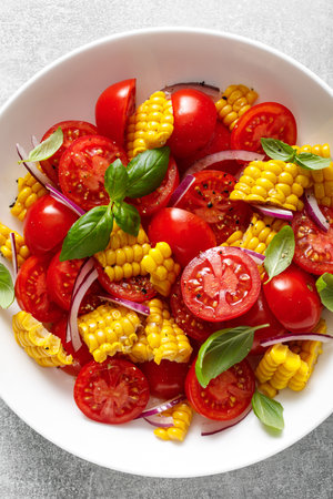 Tomato and corn salad with fresh basil, onion, dressed with olive oil. Mexican food, tomato corn salad Esquites, top viewの写真素材
