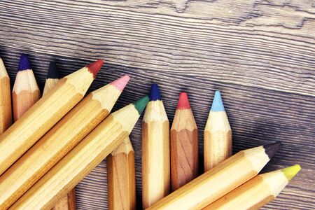 many different colored pencils with wooden background