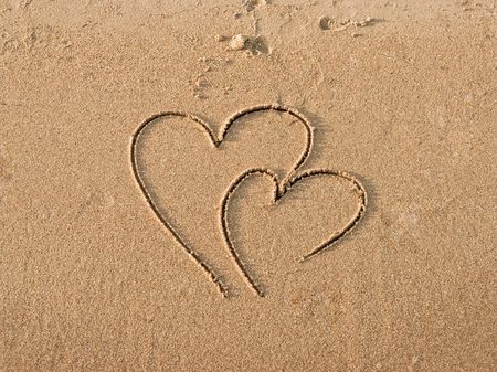 Two connected hearts drawn on wet sandの写真素材