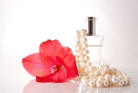 Bottle with perfume, a pearl necklace and a red flowerの写真素材