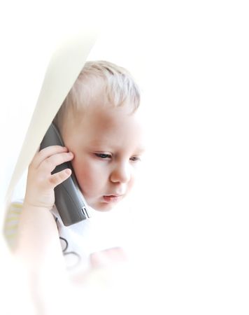The beautiful child on a white background speaking by phoneの写真素材