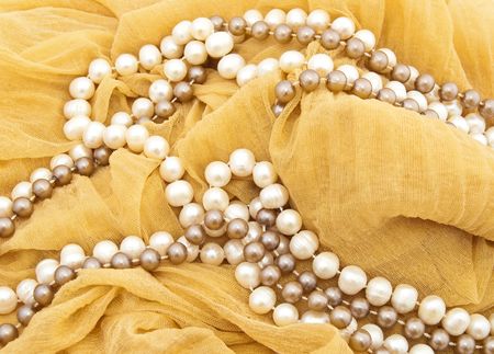 Necklaces from white and beige pearls against a scarfの写真素材