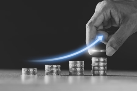 Many coins are stacked together and there are digital graphs about financial growth.の写真素材