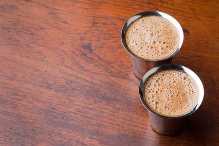 Frothy South Indian coffee served in steel glasses - background with space for textの写真素材