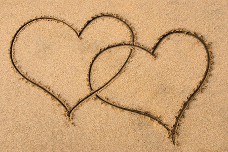 Two entangled hearts drawn out on a sandy beachの写真素材