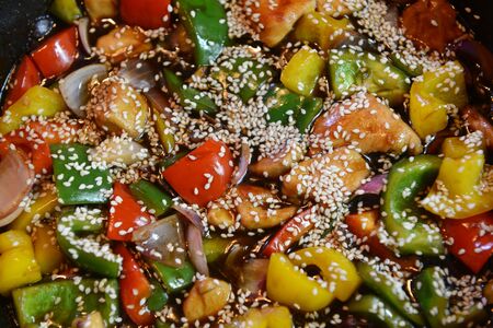 Freshly prepared stir fry with chicken and vegetables including onions, red, yellow and green capsicum in a wokの写真素材