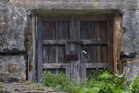 Old wooden door or gate and metal wires of the rusted lock. Outside the house, village, nature, everything comes into disrepairの写真素材