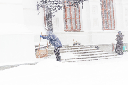 Woman cleaning snow with shovel in winter day. Snow stormの写真素材