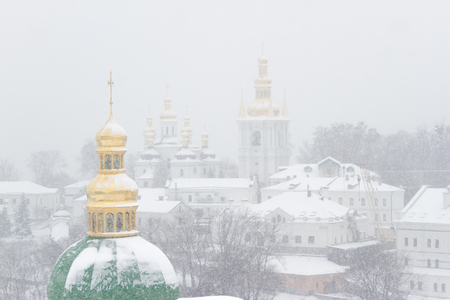 Golden and green domes of Lavra Cathedral in Kiev, low angle. At winter day, snow. Cupola snow coveredの写真素材