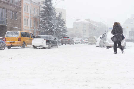 Adult man passing the winter city road in heavy snowy storm.