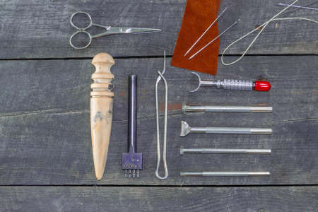 Flat set of leather tool kit for beginners. Leather instrument manual set on wood background. Filters. Leather edge burnisherの写真素材