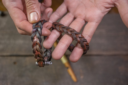 Bracelet leather handicraft. Pigtail accessory. Man s hands making handicraft leather on beautiful...