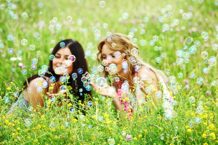 girlfriends on green grass field in soap bubblesの写真素材