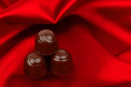 chocolate candy on red satin backgroundの写真素材