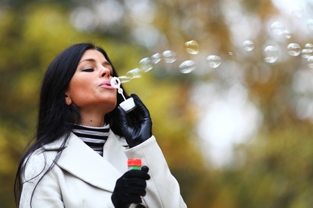 autumn woman blow bubbles portrait in parkの写真素材