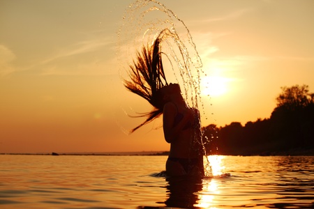 ocean woman in sunrise light splashing hairの写真素材