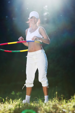 woman rotates hoop on nature backgroundの写真素材