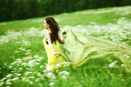 girl run by field fabric in hands fly behind like wingsの写真素材