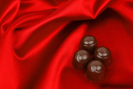chocolate candy on red satin backgroundの写真素材