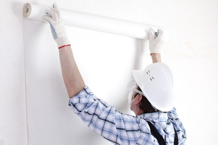 worker attaching wallpaper to wallの写真素材