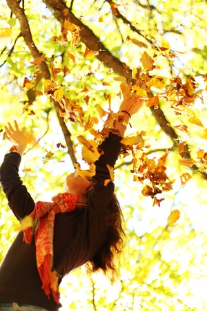 woman drop up leaves in autumn parkの写真素材
