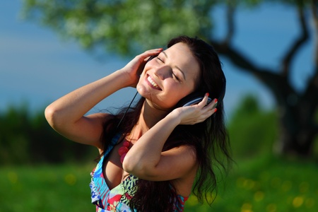 Young woman with headphones listening to music on fieldの写真素材