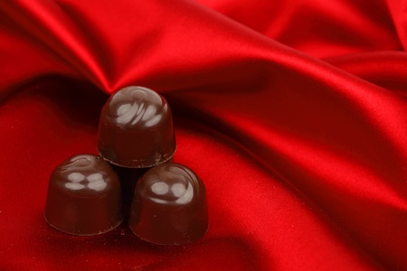 chocolate candy on red satin backgroundの写真素材