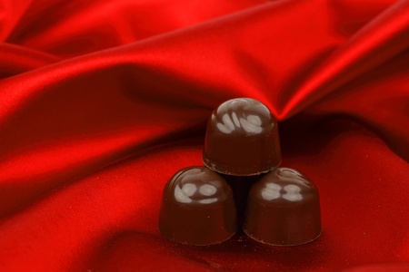 chocolate candy on red satin backgroundの写真素材
