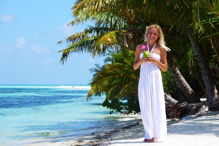 woman with a coconut cocktail on a tropical shoreの写真素材