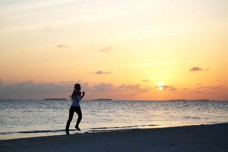 woman run along the sea coast of sunrise behindの写真素材