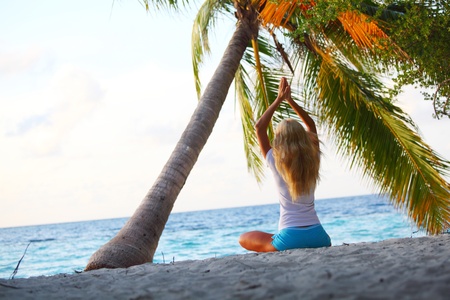 yoga woman on sea coast under palmの写真素材