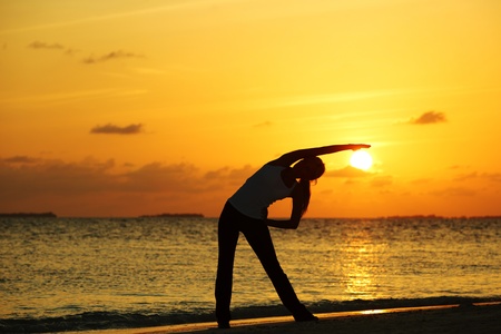 sunset yoga woman on sea coastの写真素材