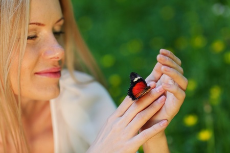 Woman playing with a butterfly on green grassの写真素材