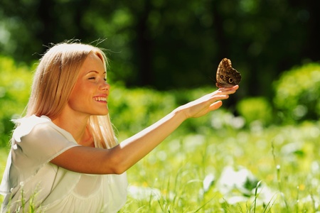 Woman playing with a butterfly on green grassの写真素材