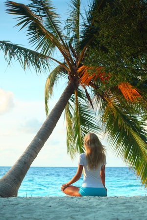 yoga woman on sea coast under palmの写真素材