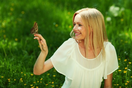 Woman playing with a butterfly on green grassの写真素材