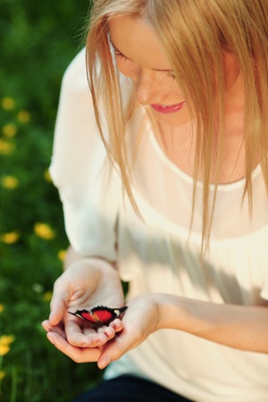 Woman playing with a butterfly on green grassの写真素材