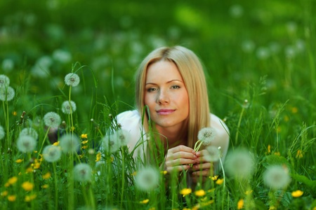 girl with a dandelion in his hand lying on the grassの写真素材