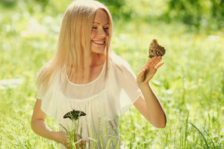 Woman playing with a butterfly on green grassの写真素材