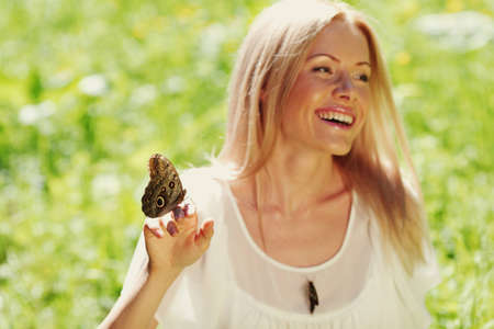 Woman playing with a butterfly on green grassの写真素材