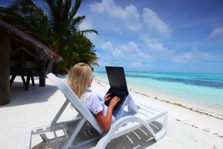 business woman with laptop lying on a chaise lounge in the tropical ocean coastの写真素材