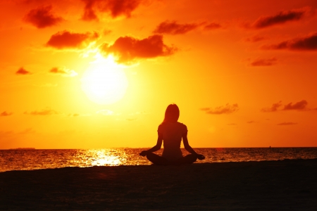 sunset yoga woman on sea coastの写真素材