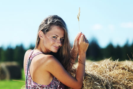 portrait of a girl next to a stack of hay under the blue skyの写真素材
