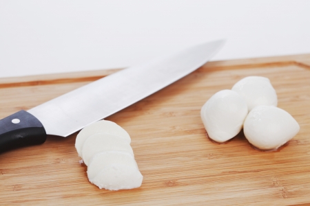 Sliced mozzarella with knife on wooden boardの写真素材