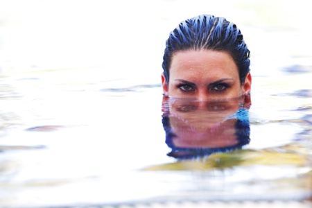 Beautiful wooman ;ookin out from water in swimming poolの写真素材