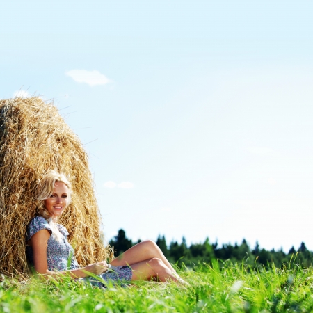 portrait of a girl next to a stack of hay under the blue skyの写真素材